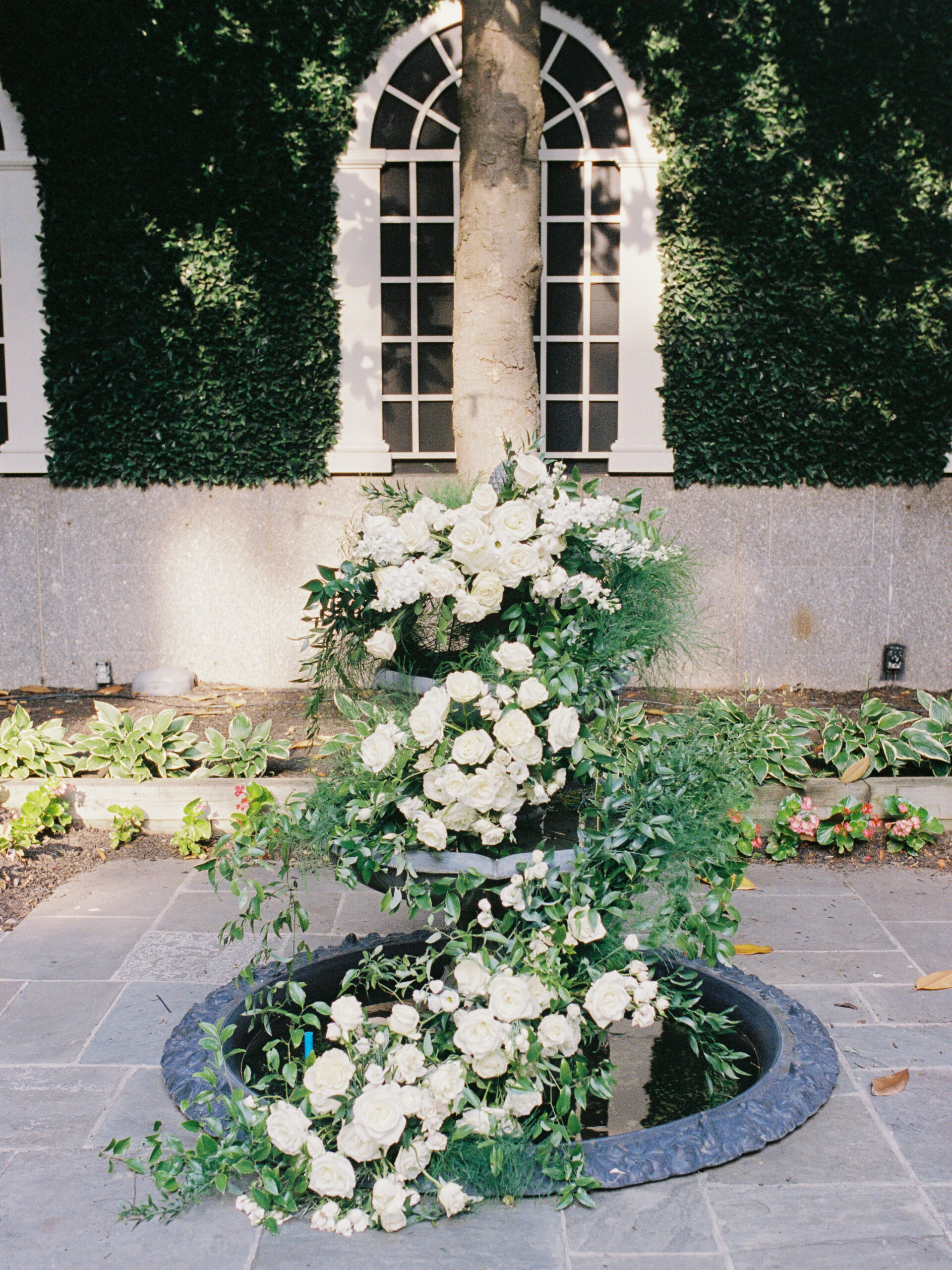 Three-tier fountain ceremony backdrop with lush white florals and greenery